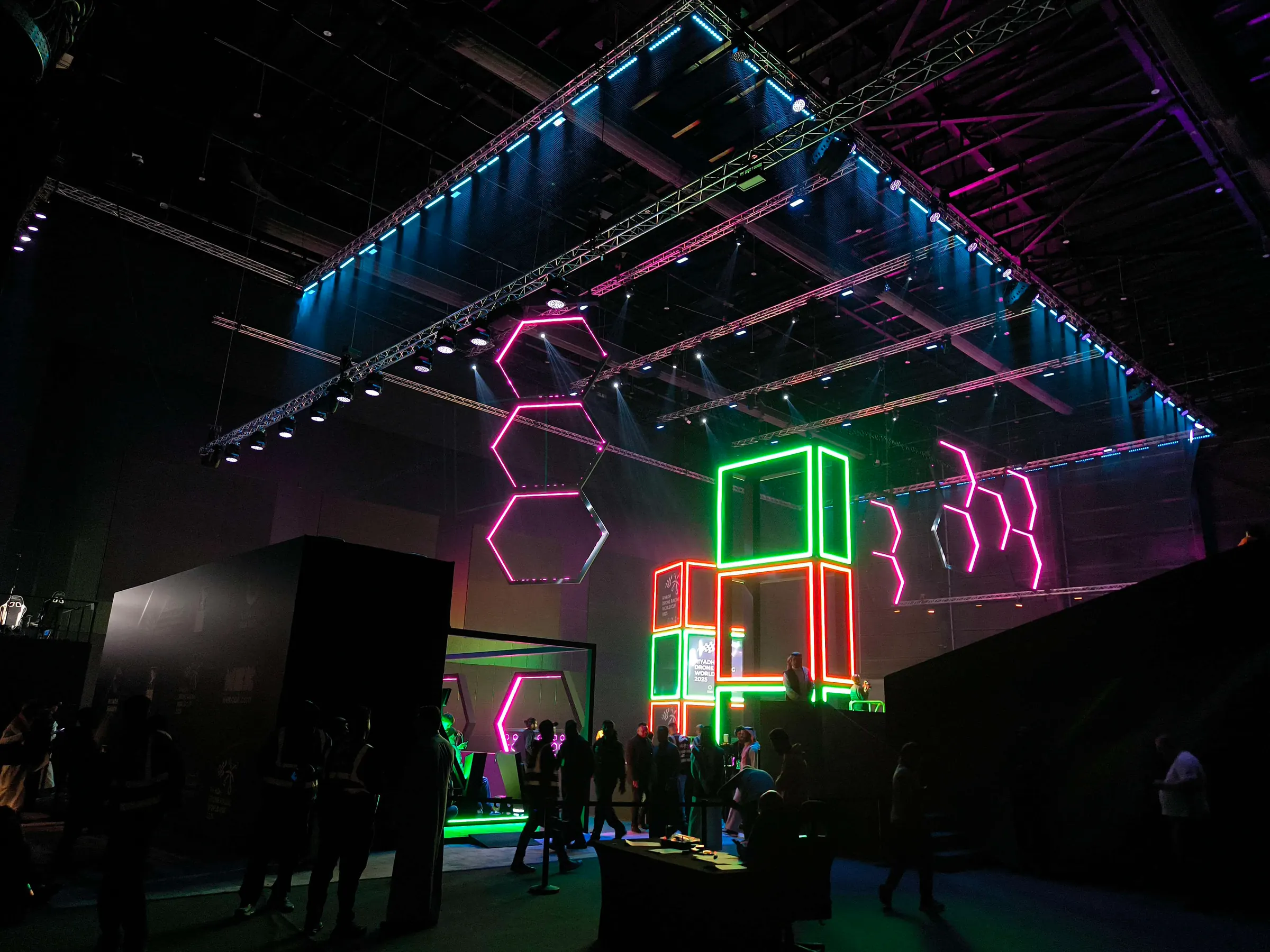 The Riyadh drone racing arena at night, lit with neon gates and truss lighting